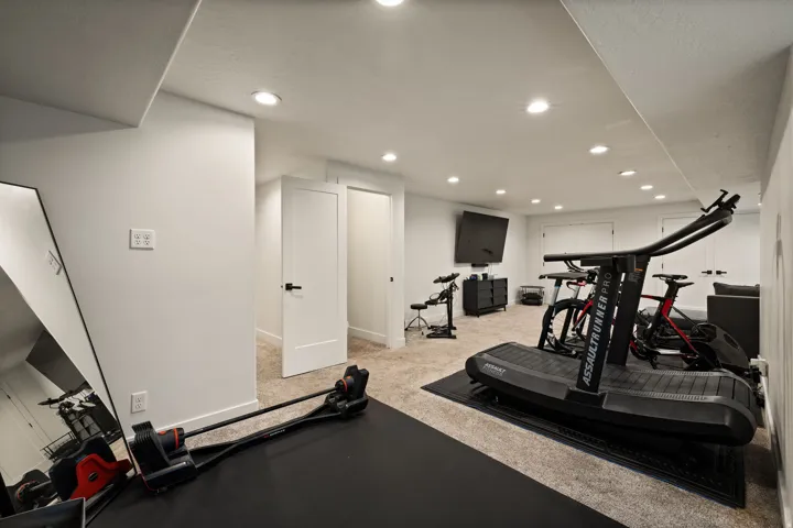 Open-concept lower level with recessed lighting, light-toned carpeting, and white walls