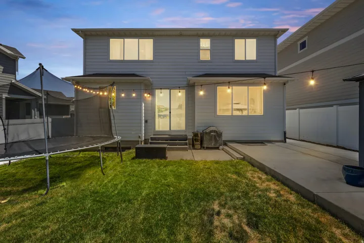 Rear exterior featuring horizontal siding, a ground-level patio, and a grass lawn