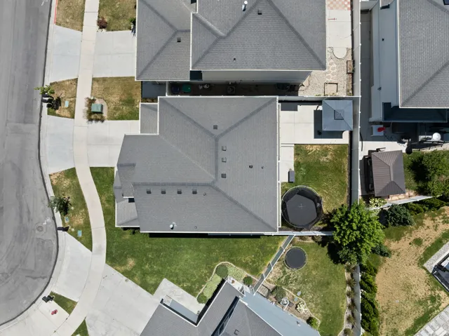 Contemporary residential property featuring a gray shingle roof, extensive concrete paving, and a manicured lawn