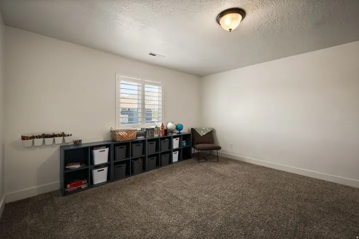 Spacious room featuring textured carpeting and white walls
