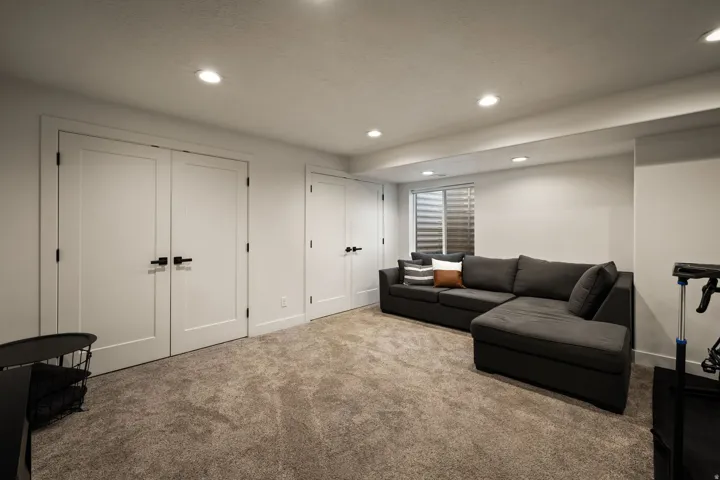 Recessed lighting illuminates this carpeted room featuring white walls and multiple white panel doors with black hardware