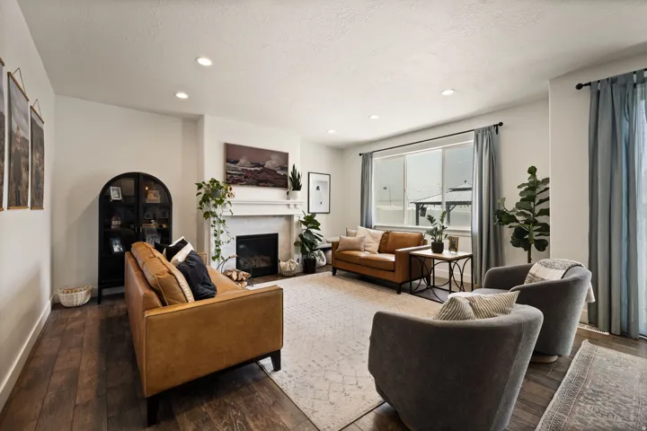 Living room featuring wood-finish flooring, recessed lighting, and a fireplace with a stone surround and mantel