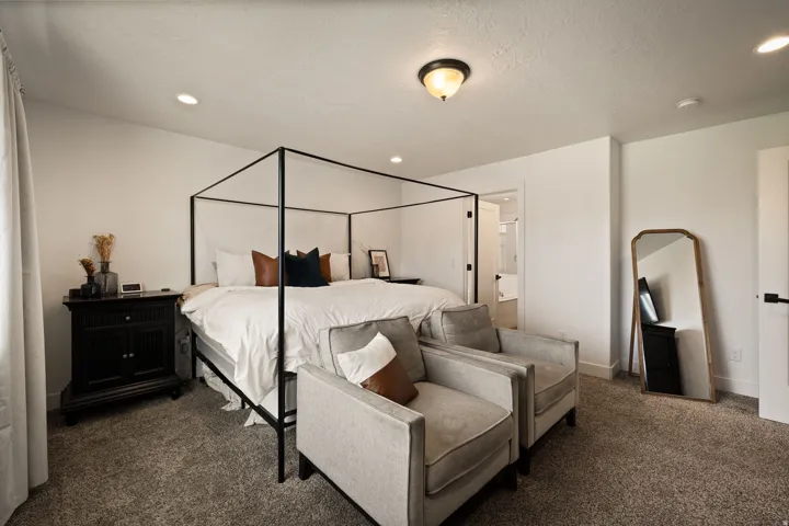 Spacious bedroom featuring neutral wall tones, recessed lighting, and a ceiling-mounted light fixture