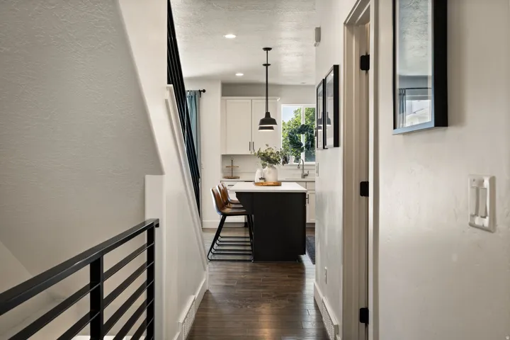 Hallway featuring dark wood-finish flooring, white walls, and a modern horizontal metal railing