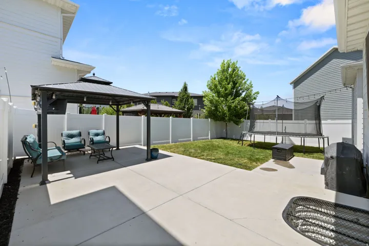 Expansive concrete patio area with a built-in gazebo featuring a dark metal frame and roof