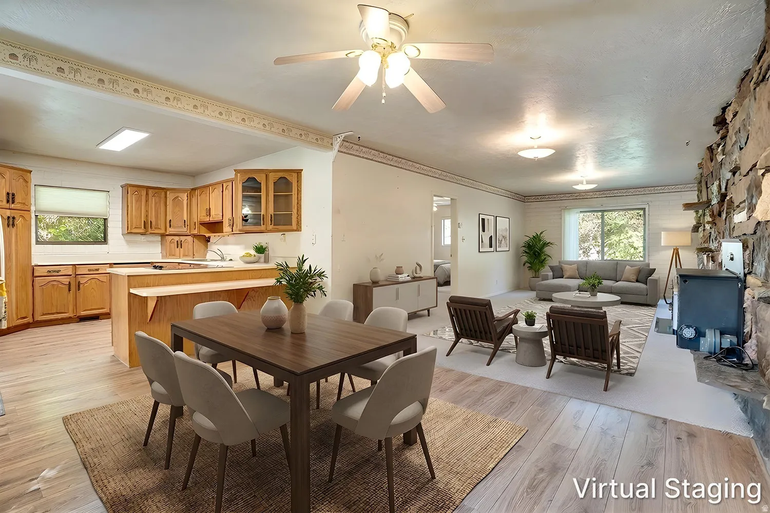 Open concept living and dining areas featuring wood-finish flooring, a stone-clad wall with an integrated fireplace, and overhead ceiling fans