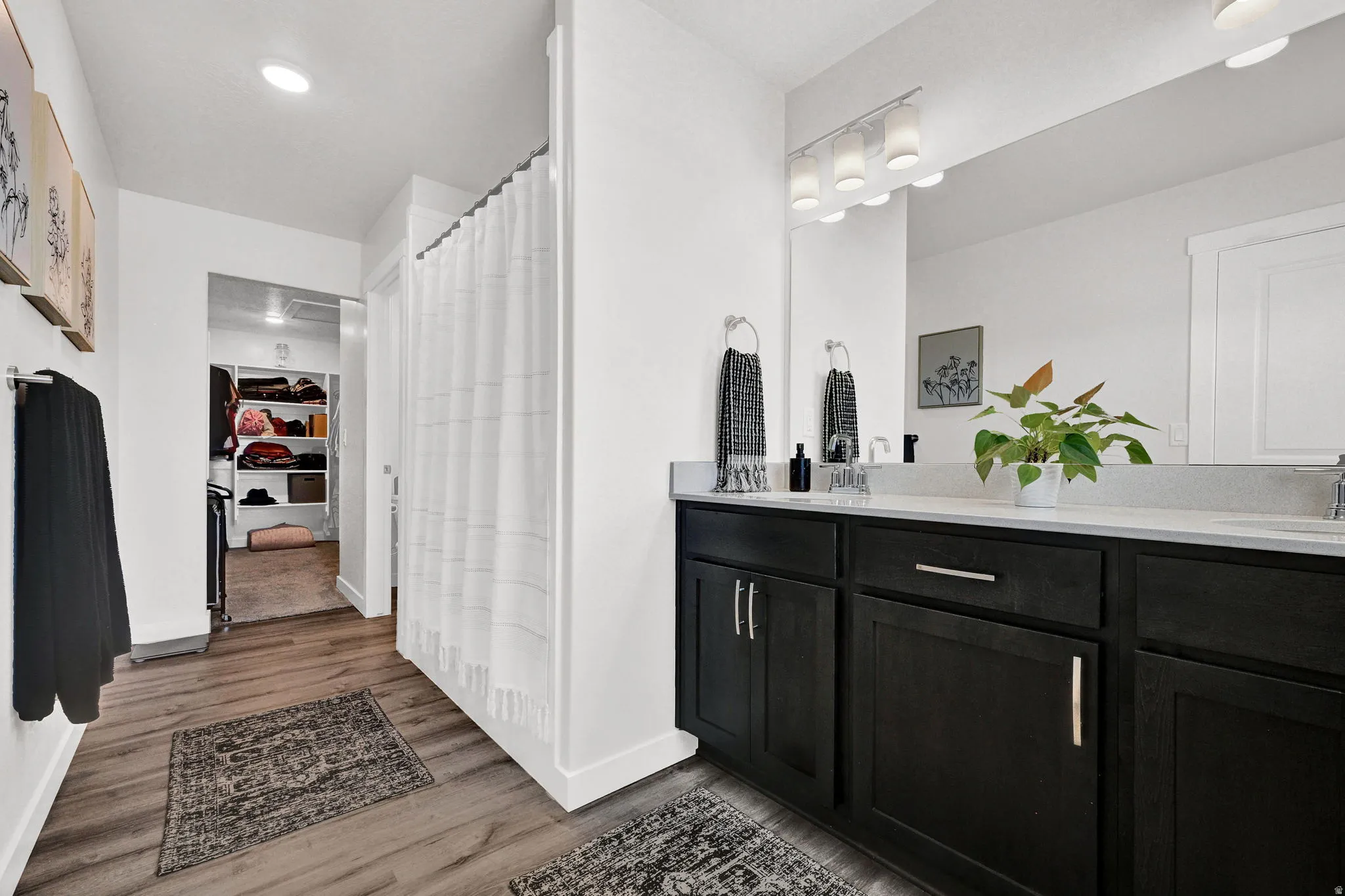Bathroom featuring a dual vanity with dark wood-finish cabinetry, light-toned countertop, and an expansive mirror