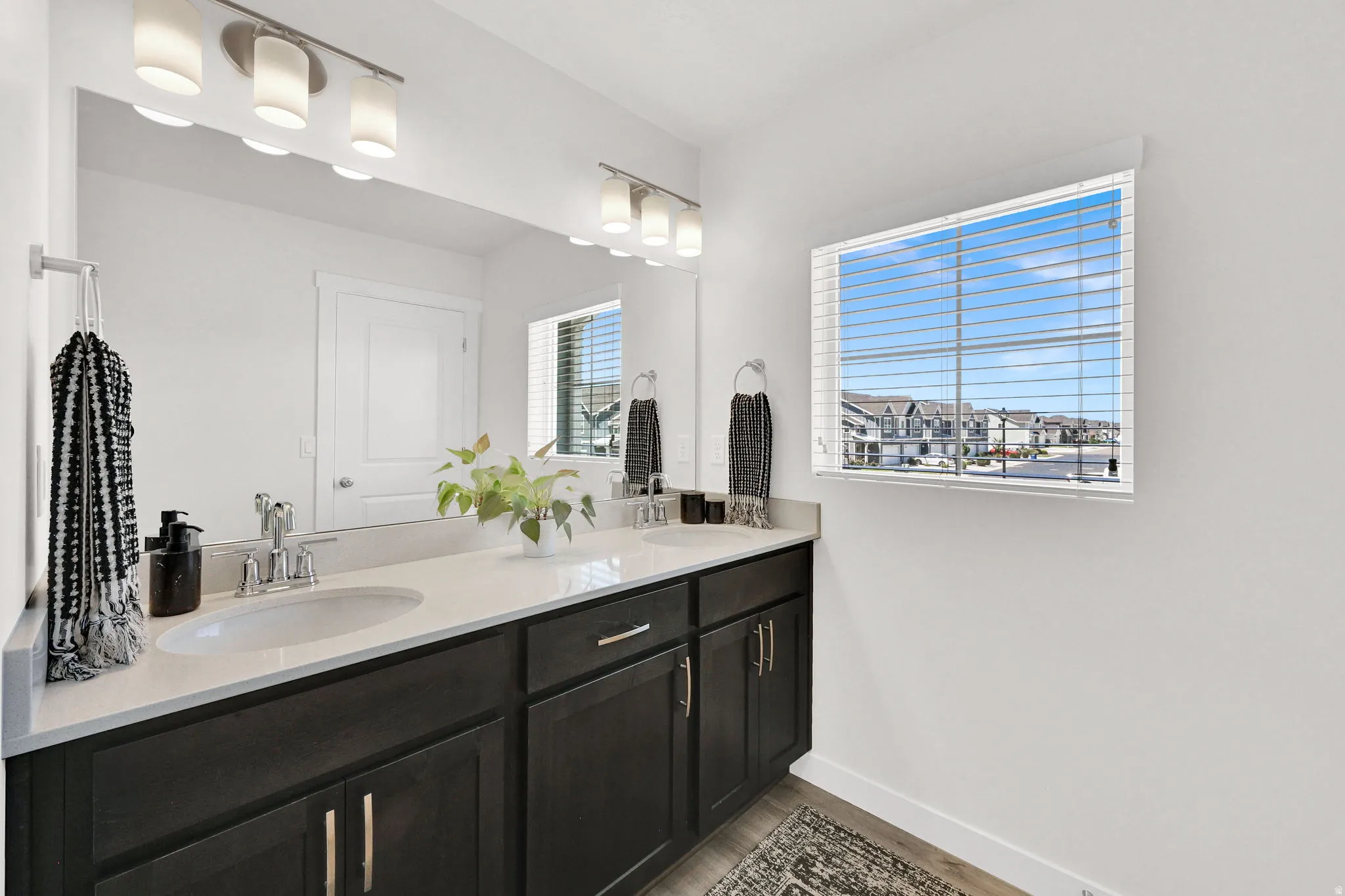 Double vanity featuring dark wood-finish cabinetry, chrome hardware, and a light-toned countertop with integrated sinks
