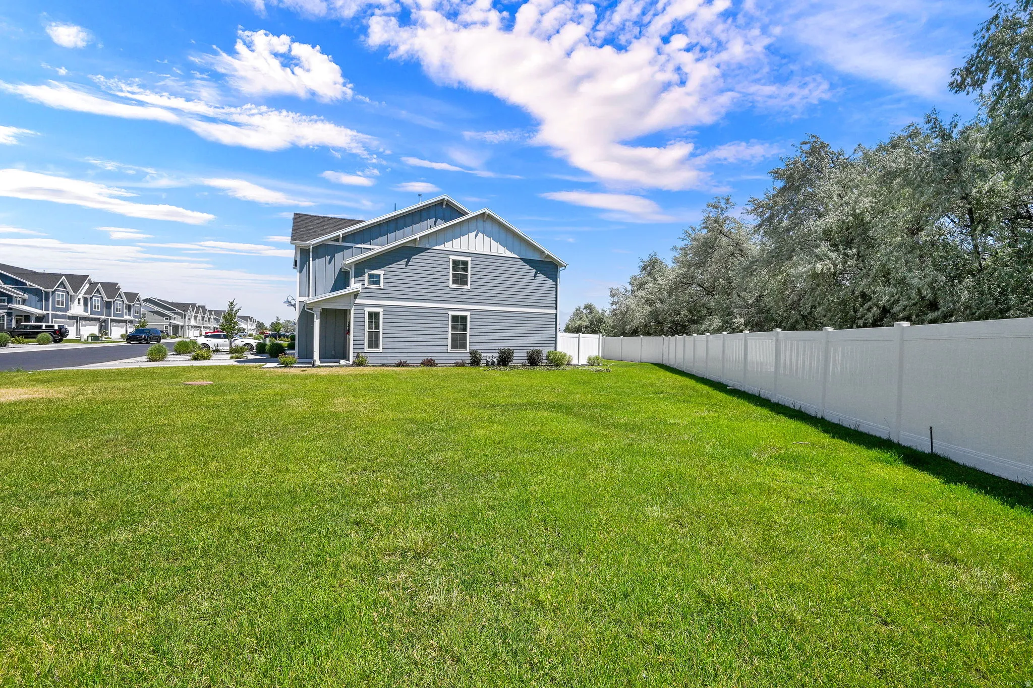 Expansive green lawn with a white privacy fence