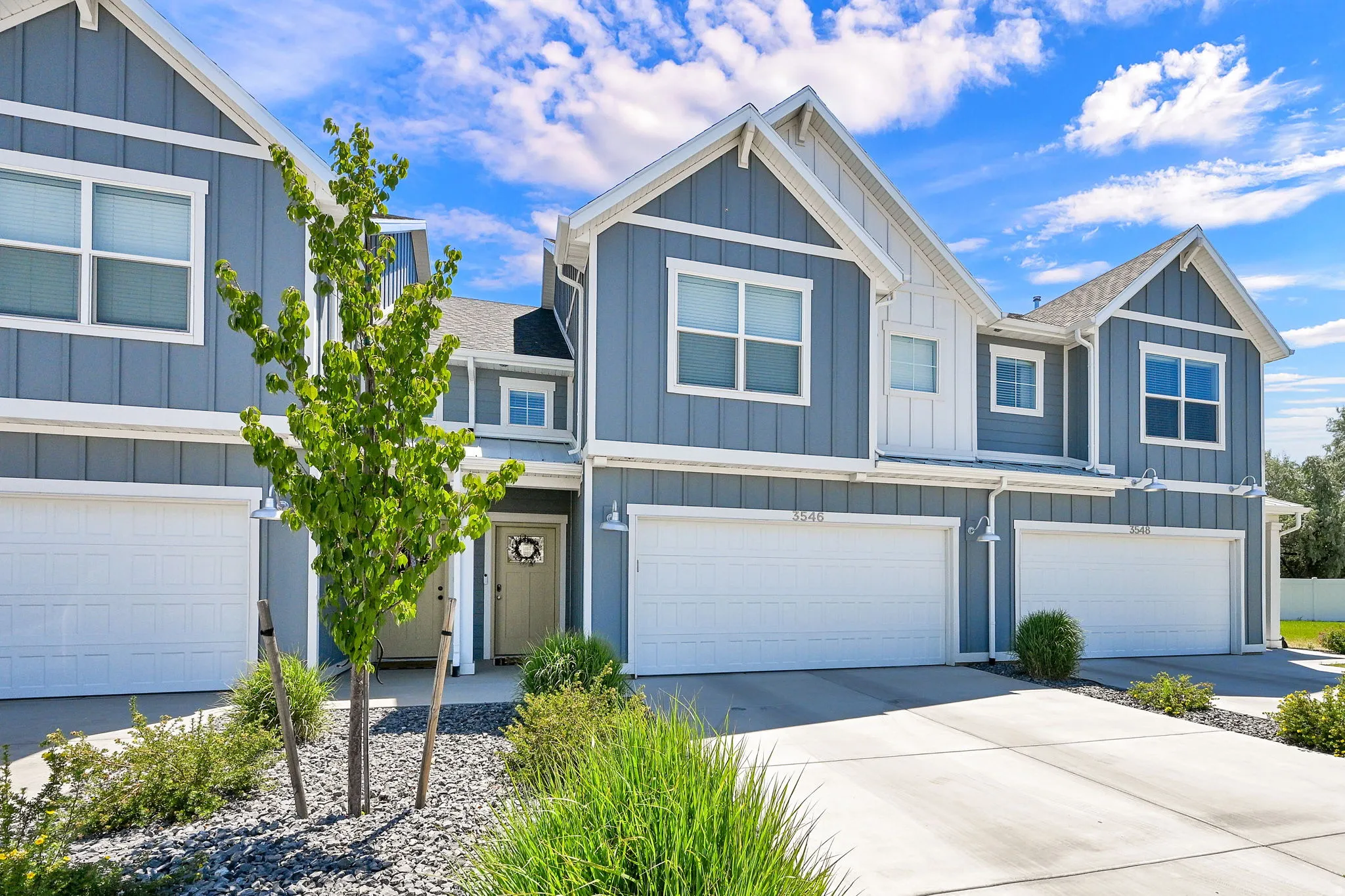 Modern townhome exterior featuring blue vertical siding, white trim, and a gabled roofline