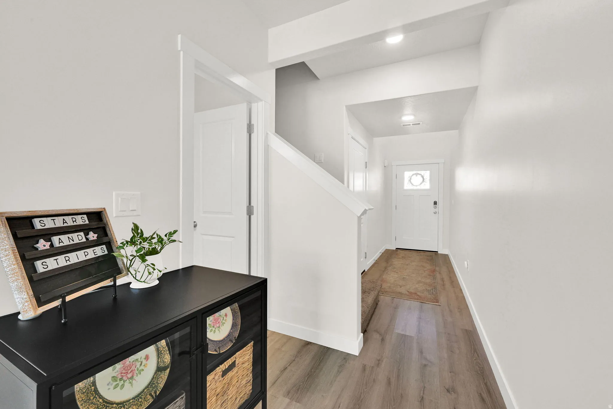 Welcoming entry with wood-finish flooring, crisp white walls, and recessed lighting
