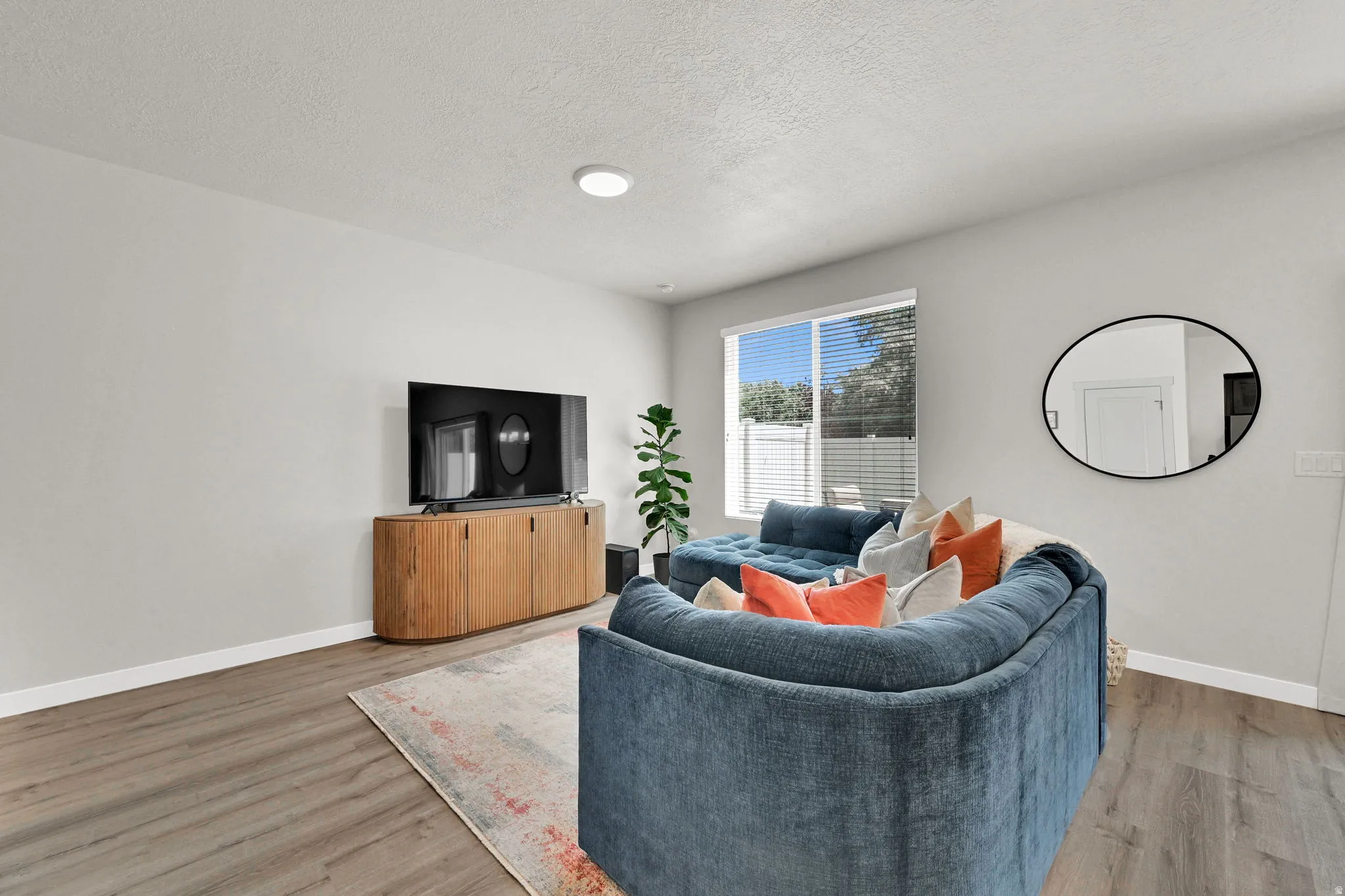 Open living area featuring light gray walls, wood-finish flooring, a contemporary window, and a recessed ceiling light