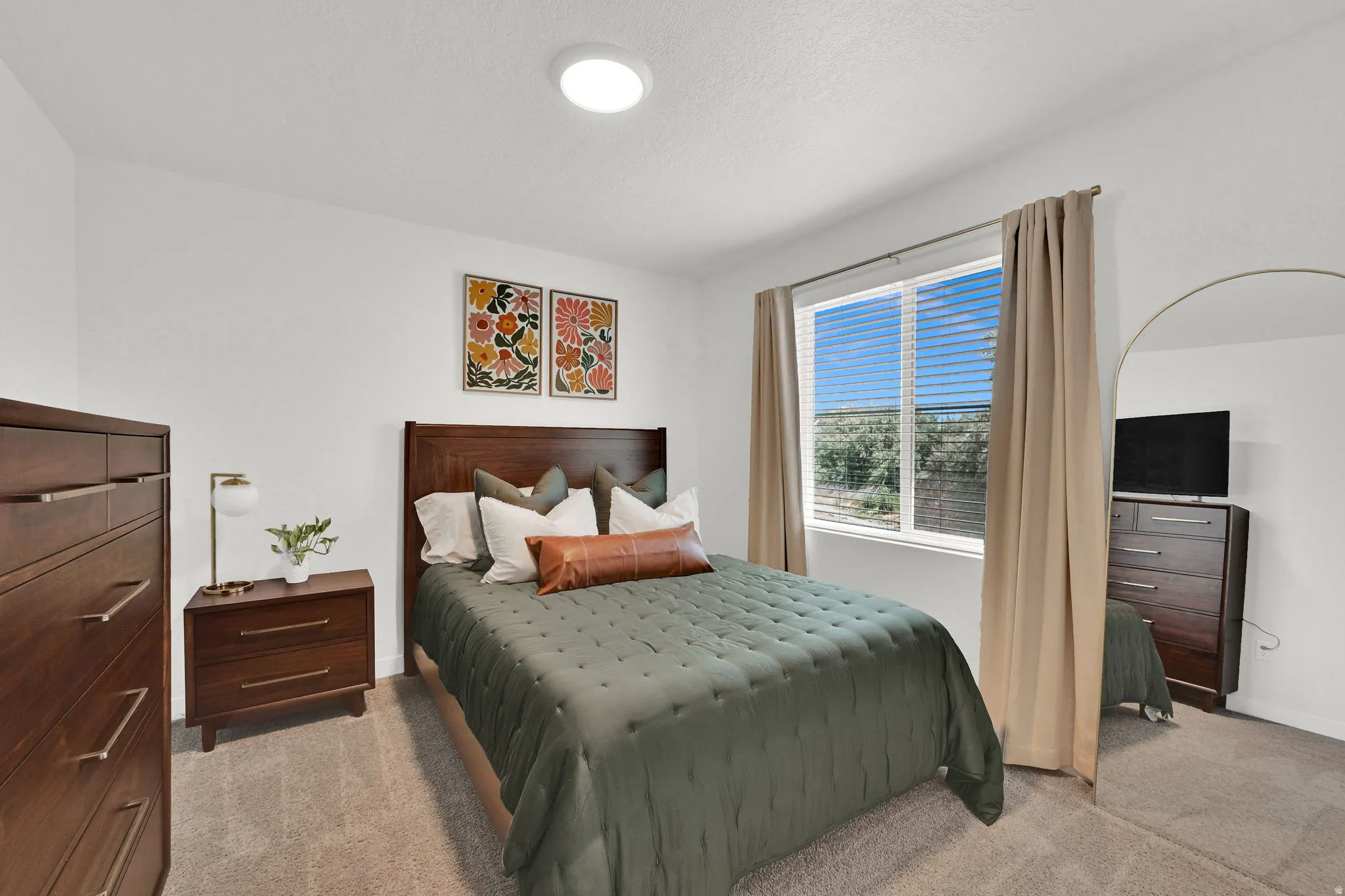 Window-lined bedroom featuring light-colored walls and neutral carpeting