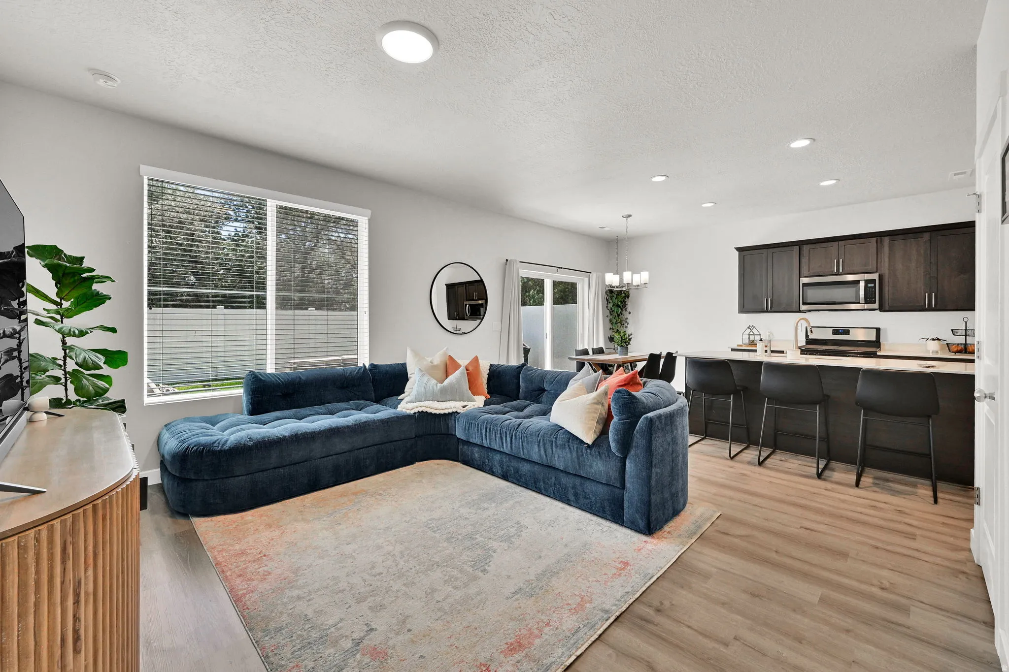 Open-concept living space featuring wood-finish flooring, recessed lighting, and a window with horizontal blinds