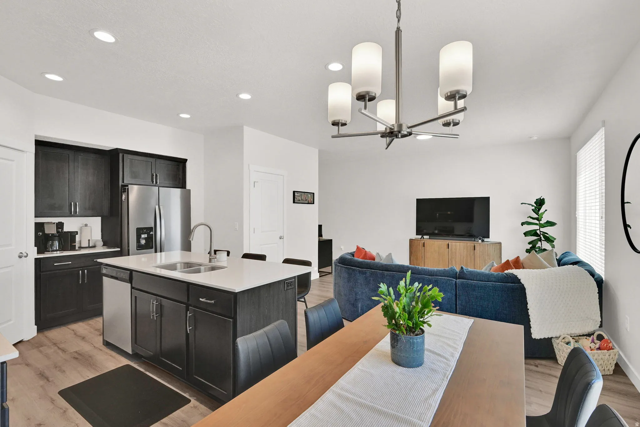 Open-concept living space featuring a kitchen island with seating, dark wood-finish cabinetry, stainless steel appliances, and recessed lighting