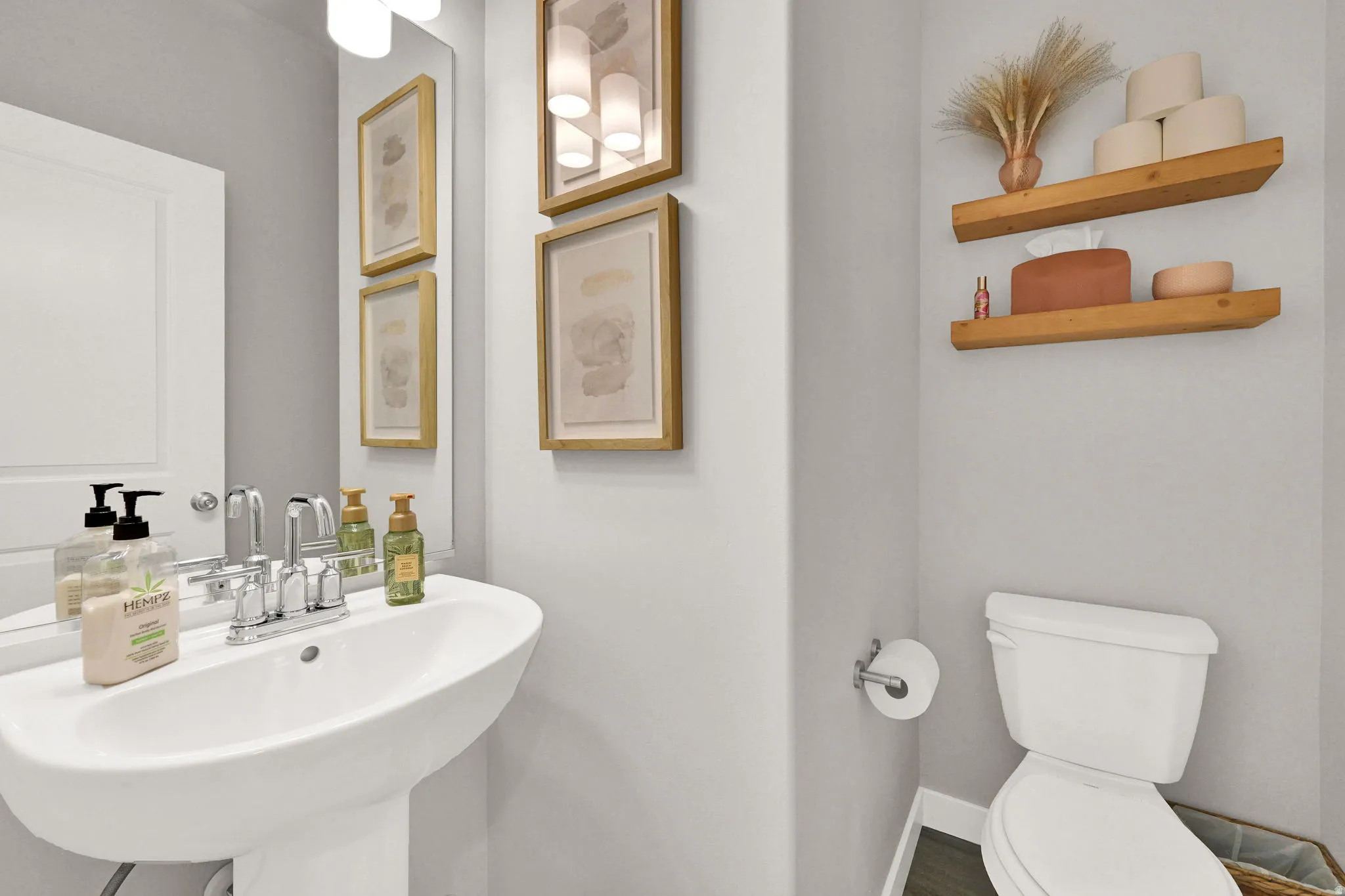 Pedestal sink with chrome faucet, complemented by a mirror and wall-mounted light fixture