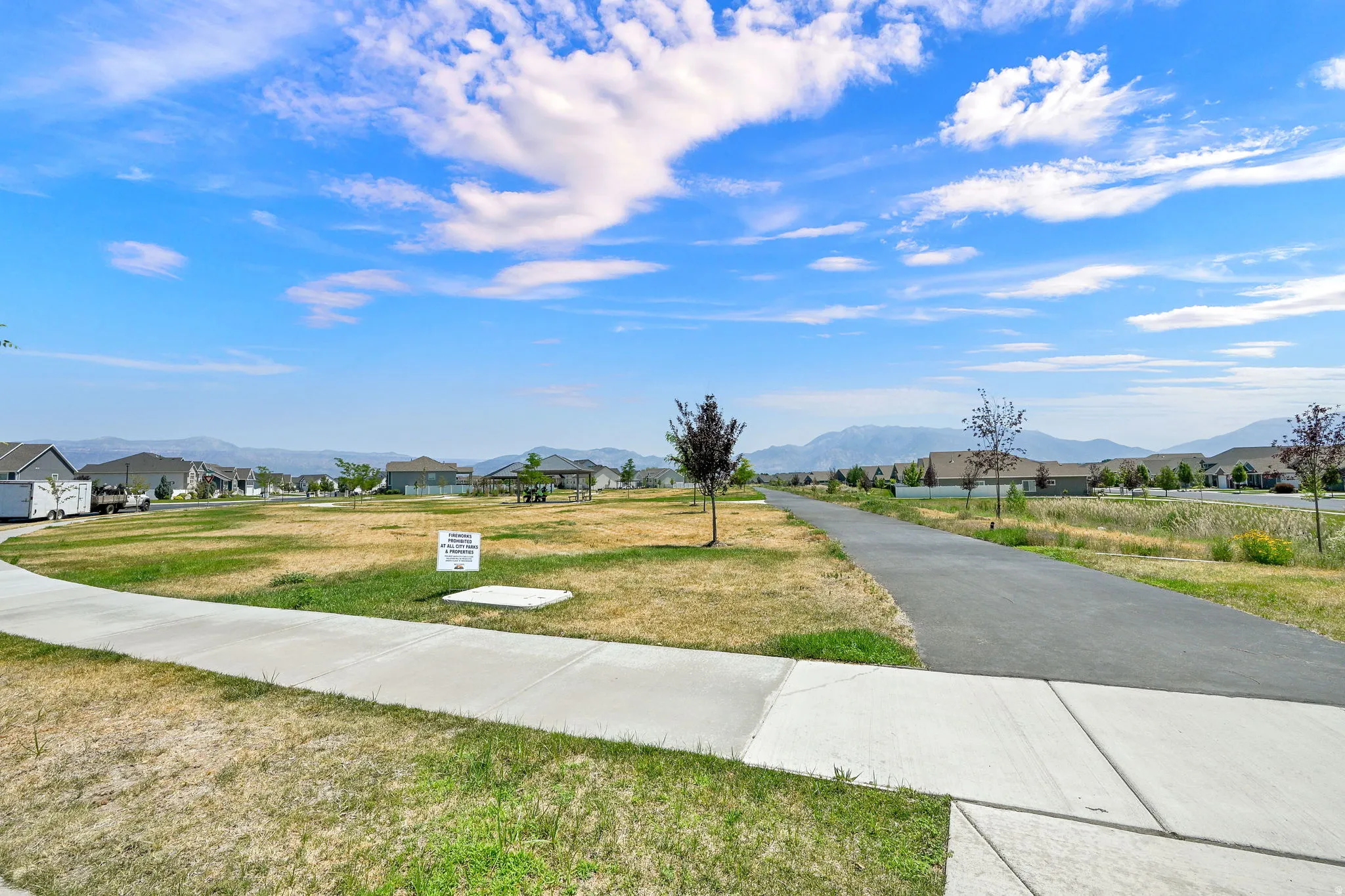 Expansive open space featuring a paved walking path, concrete sidewalks, and distant mountain ranges