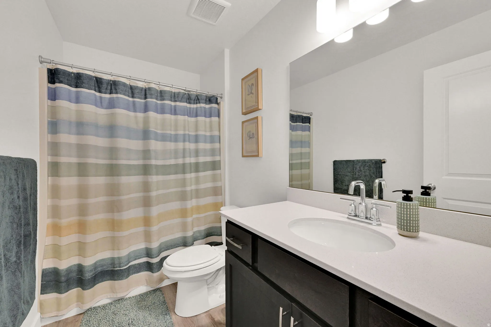 Bathroom featuring a spacious vanity with a white countertop, an undermount sink, and wood-finish flooring