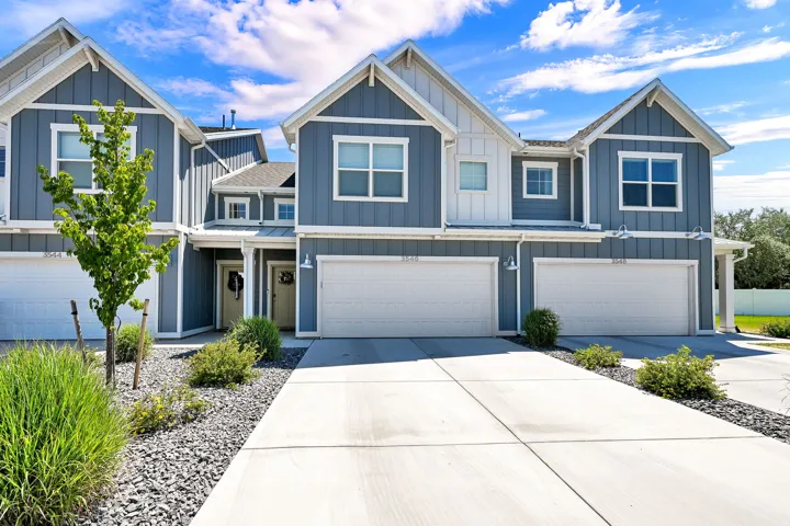 Modern townhome exterior featuring blue vertical siding, white trim, gabled roofs, and an attached two-car garage