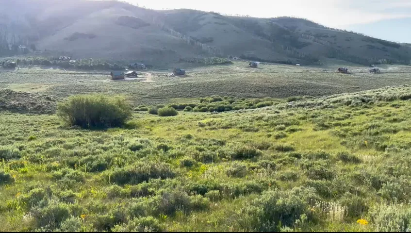 Expansive rolling landscape featuring natural greenery and distant mountain formations