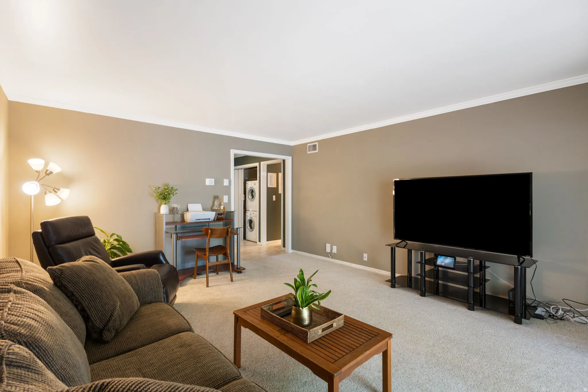 Living area featuring neutral wall tones, crown molding, and carpeted flooring