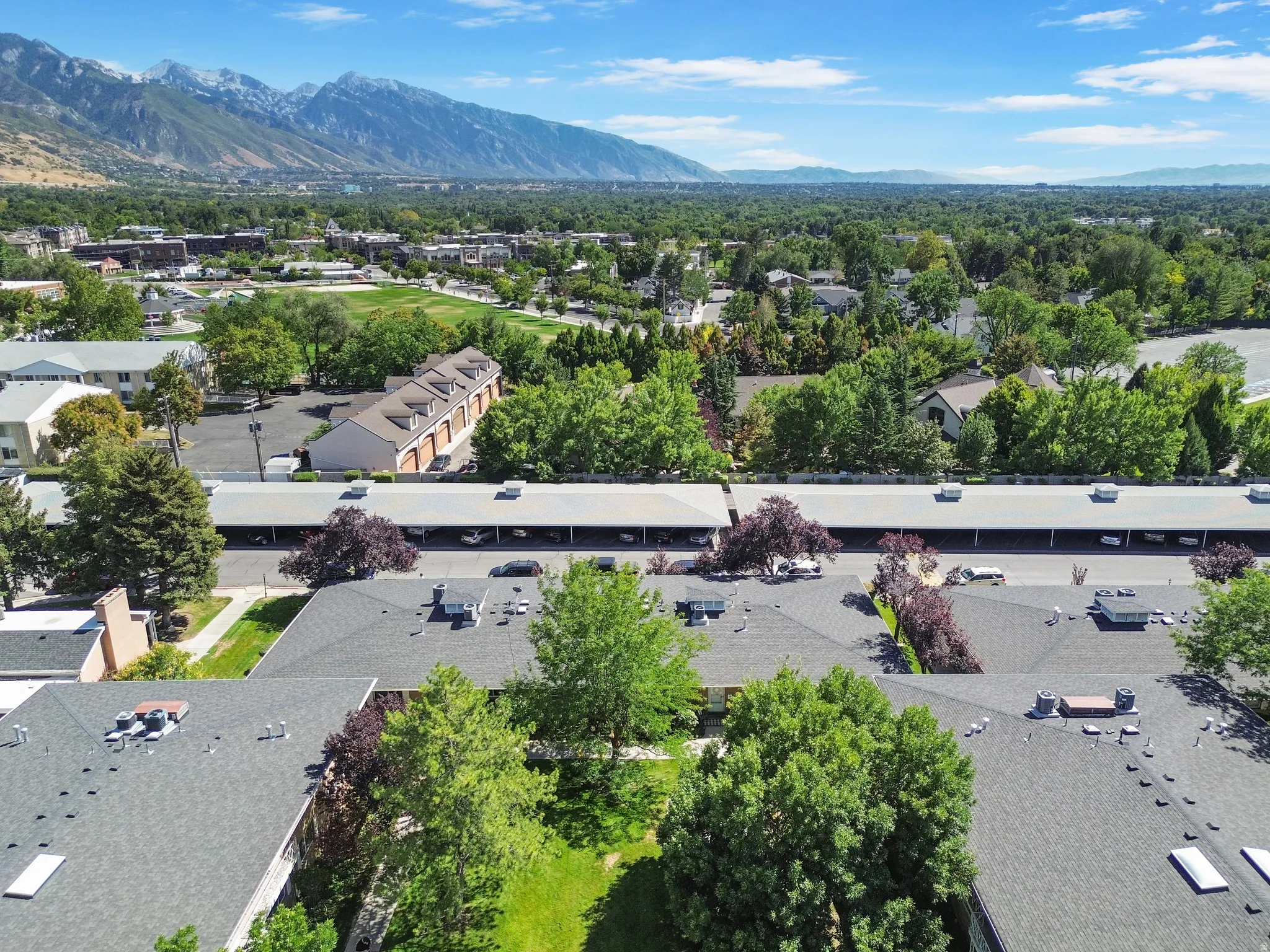 Expansive aerial perspective showcasing a developed community with residential structures, green spaces, and mountain scenery