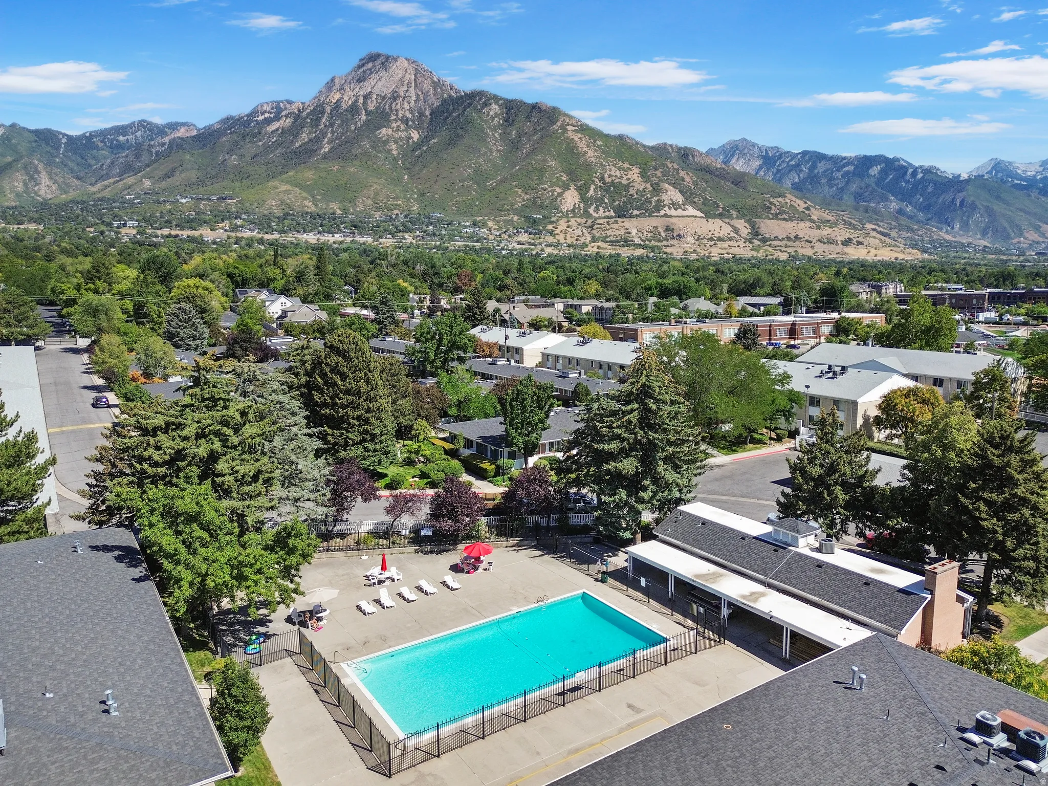 Community swimming pool featuring a surrounding paved deck, perimeter fencing, and adjacent lounge chairs