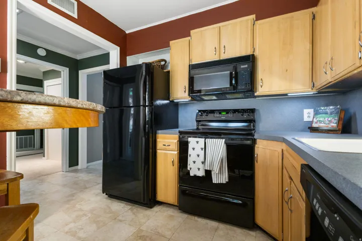 Kitchen featuring light wood cabinetry, a black appliance suite, and light-toned tile flooring