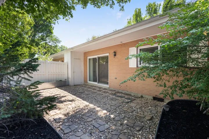 Exterior patio area featuring a brick facade, sliding glass door, and a white privacy fence