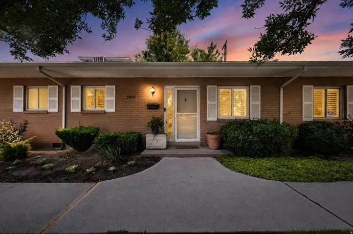 Brick facade residence featuring white window shutters and a covered entry