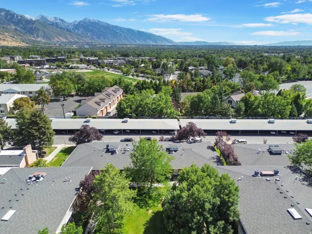 Expansive aerial perspective showcasing a developed community with residential structures, green spaces, and mountain scenery