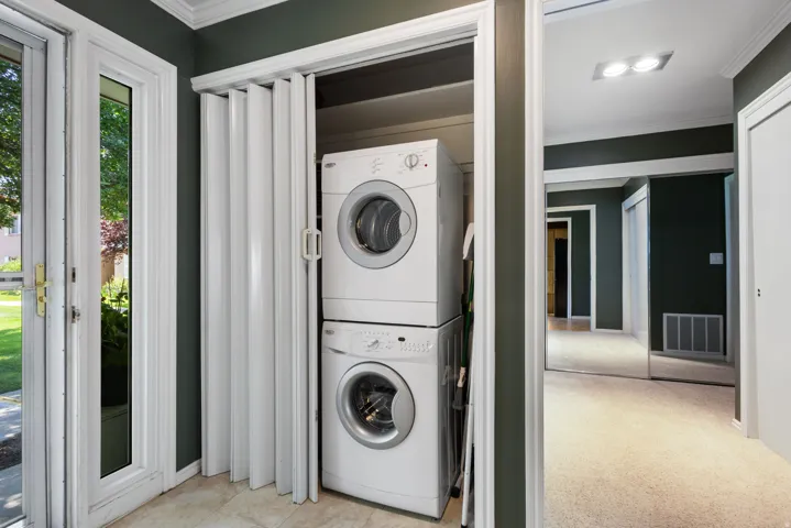 Dedicated laundry closet with stacked washer and dryer, featuring bi-fold doors