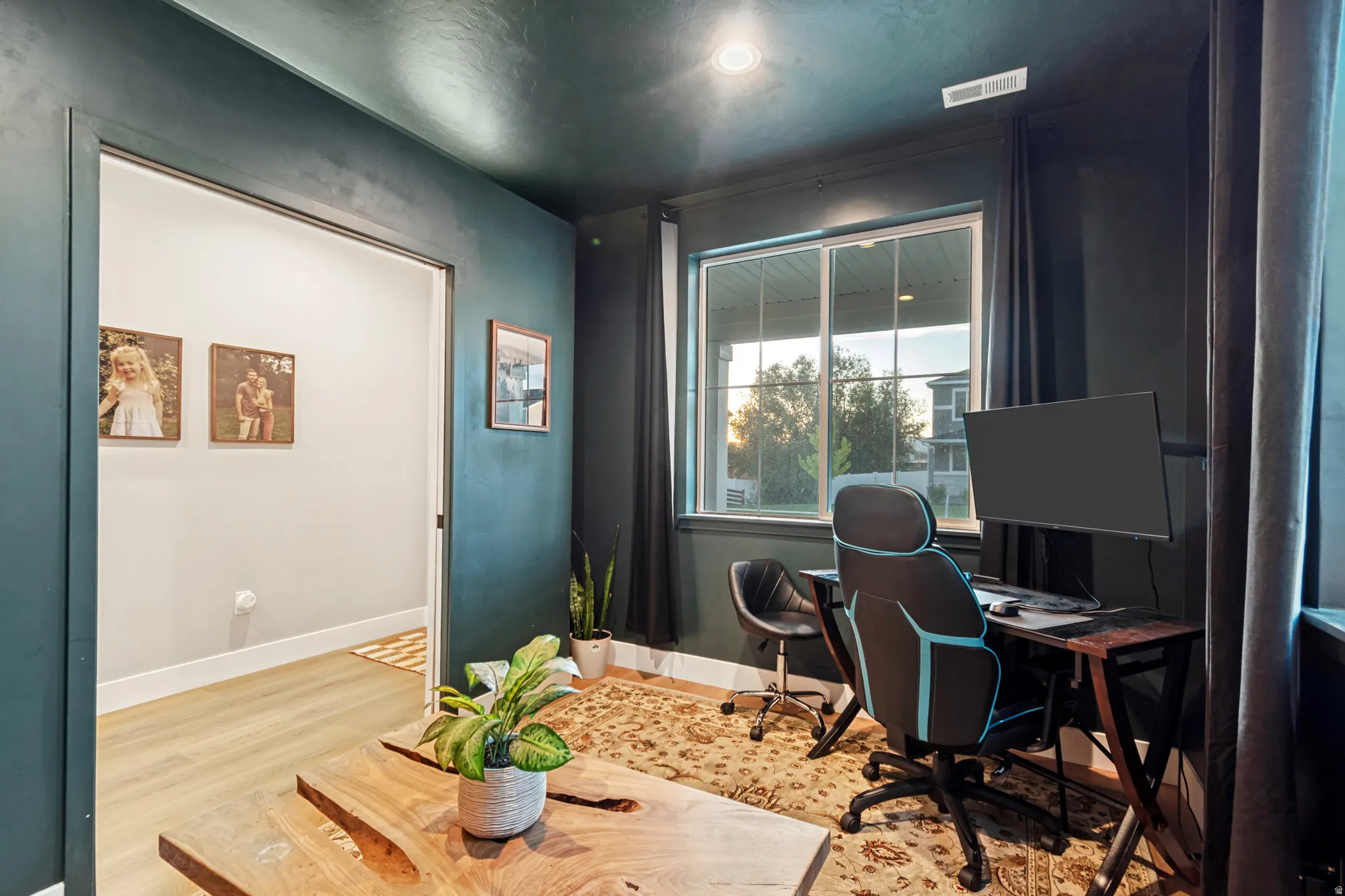 Versatile room with dark accent walls, light wood-finish flooring, and a large window