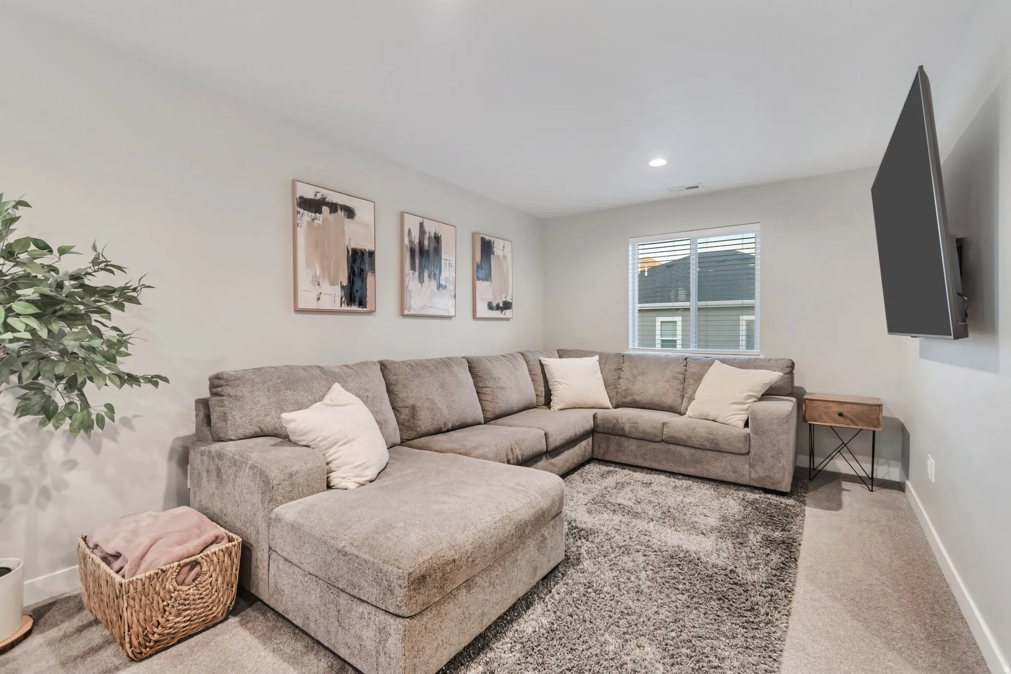 Carpeted room featuring a window with blinds, recessed ceiling lighting, and a wall-mounted television