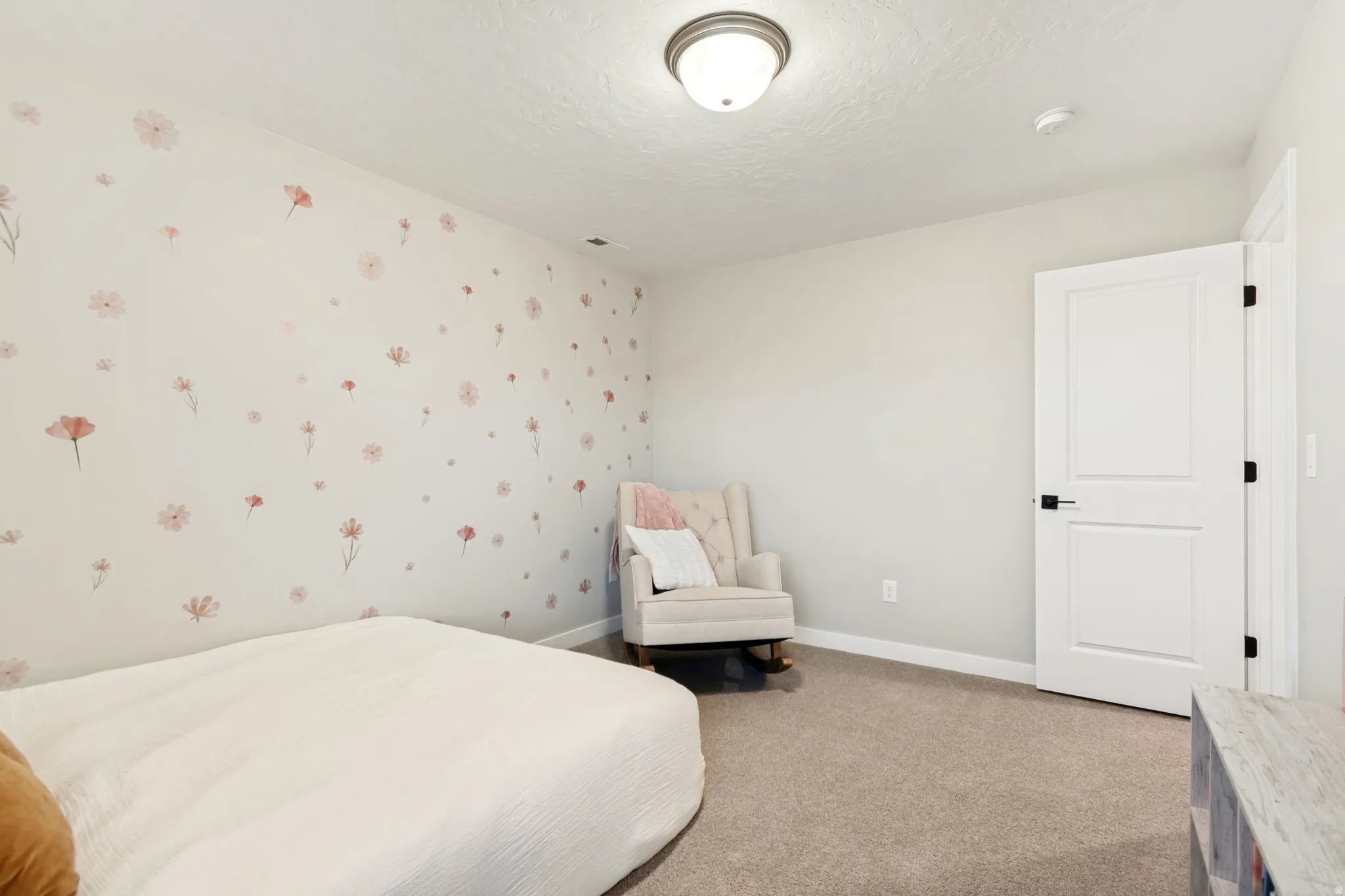 Neutral wall color with a floral accent wall, recessed lighting, white trim, and a paneled door with dark hardware