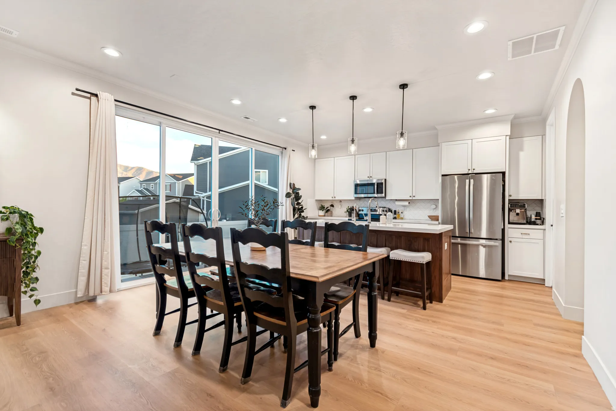Open-concept living space featuring wood-finish flooring, recessed lighting, and a kitchen with white cabinetry and stainless steel appliances