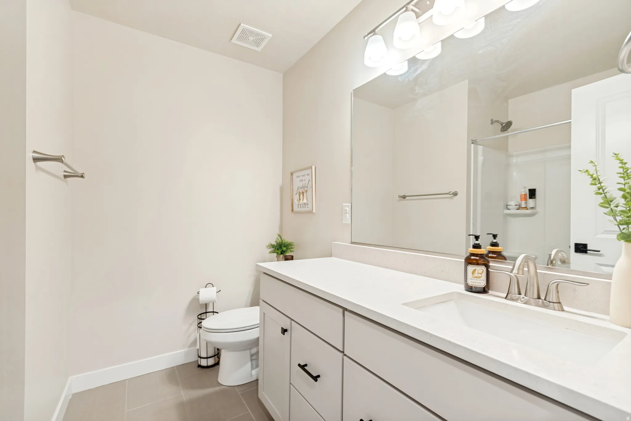 Contemporary bathroom featuring a vanity with a light-toned countertop, integrated sink, and brushed nickel faucet
