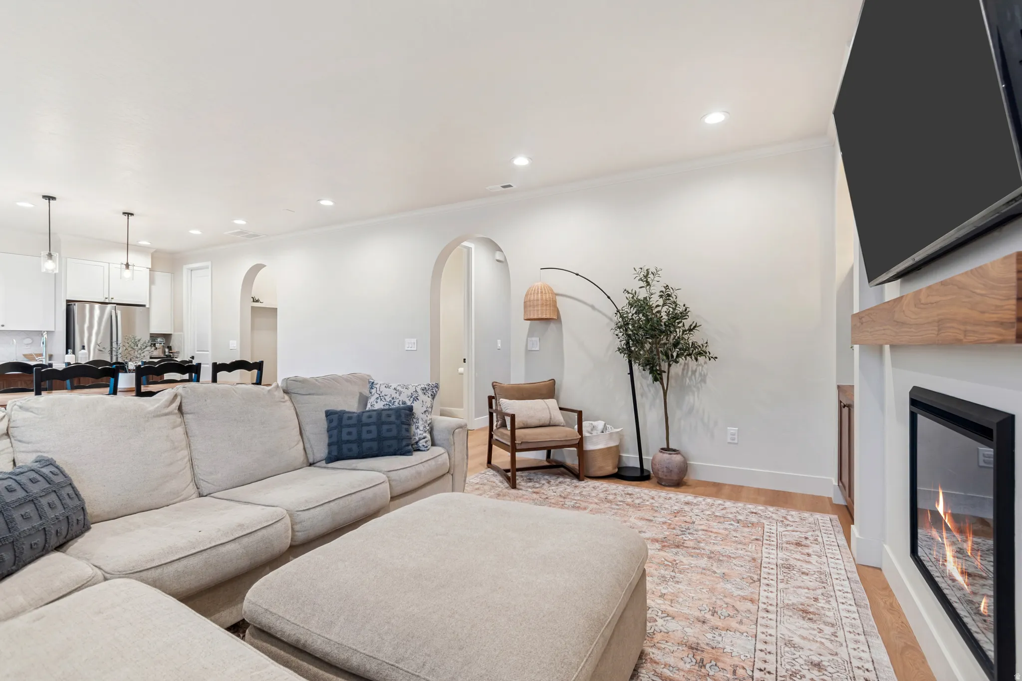Open-concept living area featuring a built-in fireplace with a wood mantel, recessed lighting, and light wood-finish flooring