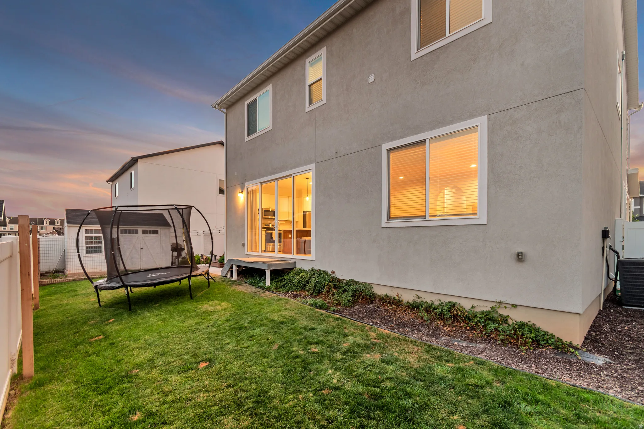 Expansive backyard featuring a manicured lawn, a sliding glass door, and a ground-level deck