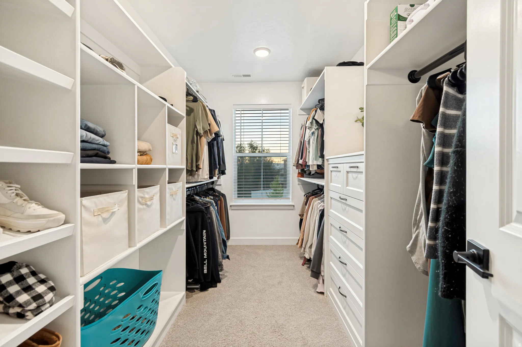Custom closet system featuring built-in shelving, hanging rods, and a central dresser unit with drawers