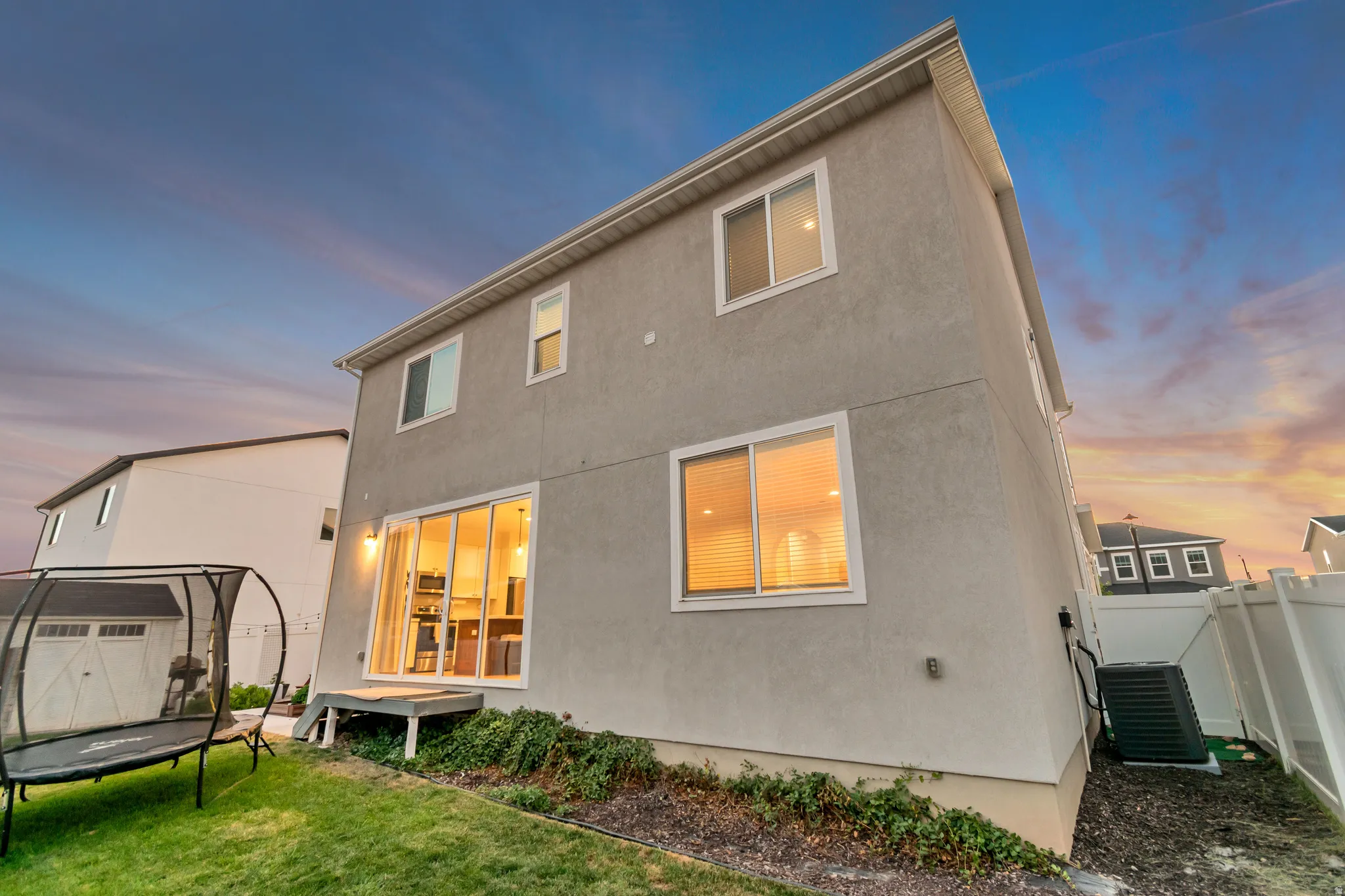 Stucco exterior featuring multiple windows and a sliding glass door