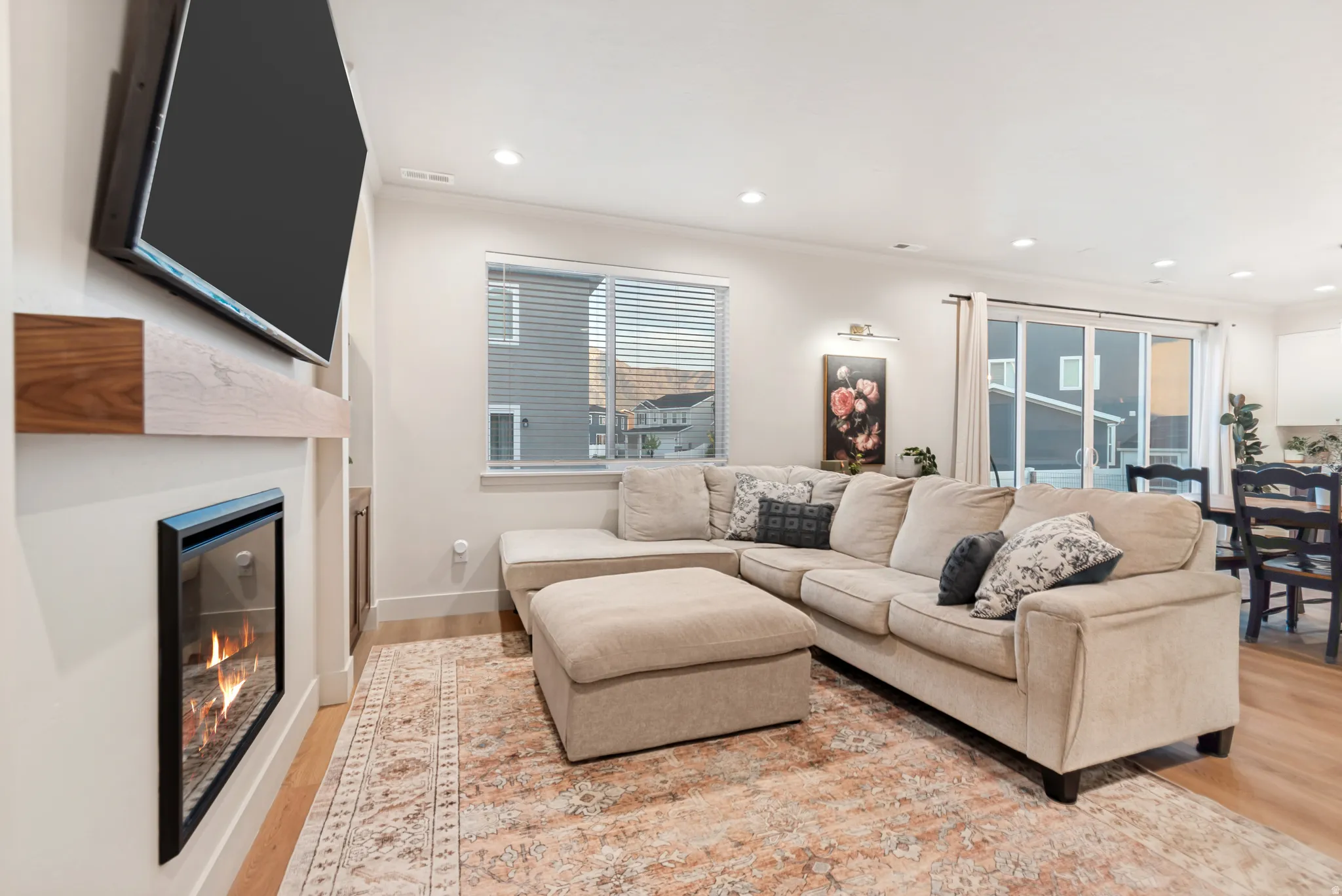 Living area featuring a wall-mounted fireplace with a wood-finish mantel, recessed lighting, and wood-finish flooring