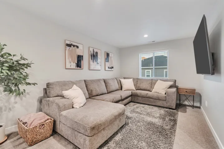 Carpeted room featuring a window with blinds, recessed ceiling lighting, and a wall-mounted television
