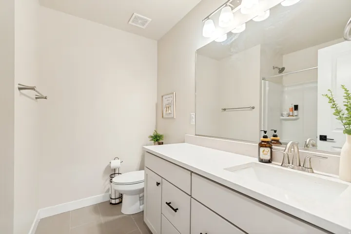 Contemporary bathroom featuring a vanity with a light-toned countertop, integrated sink, and brushed nickel faucet