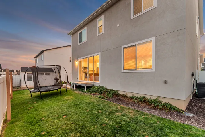 Expansive backyard featuring a manicured lawn, a sliding glass door, and a ground-level deck
