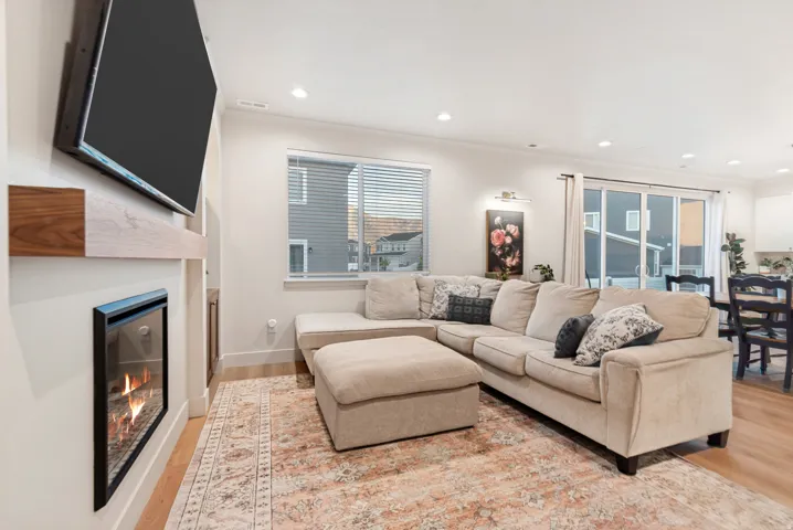 Living area featuring a wall-mounted fireplace with a wood-finish mantel, recessed lighting, and wood-finish flooring