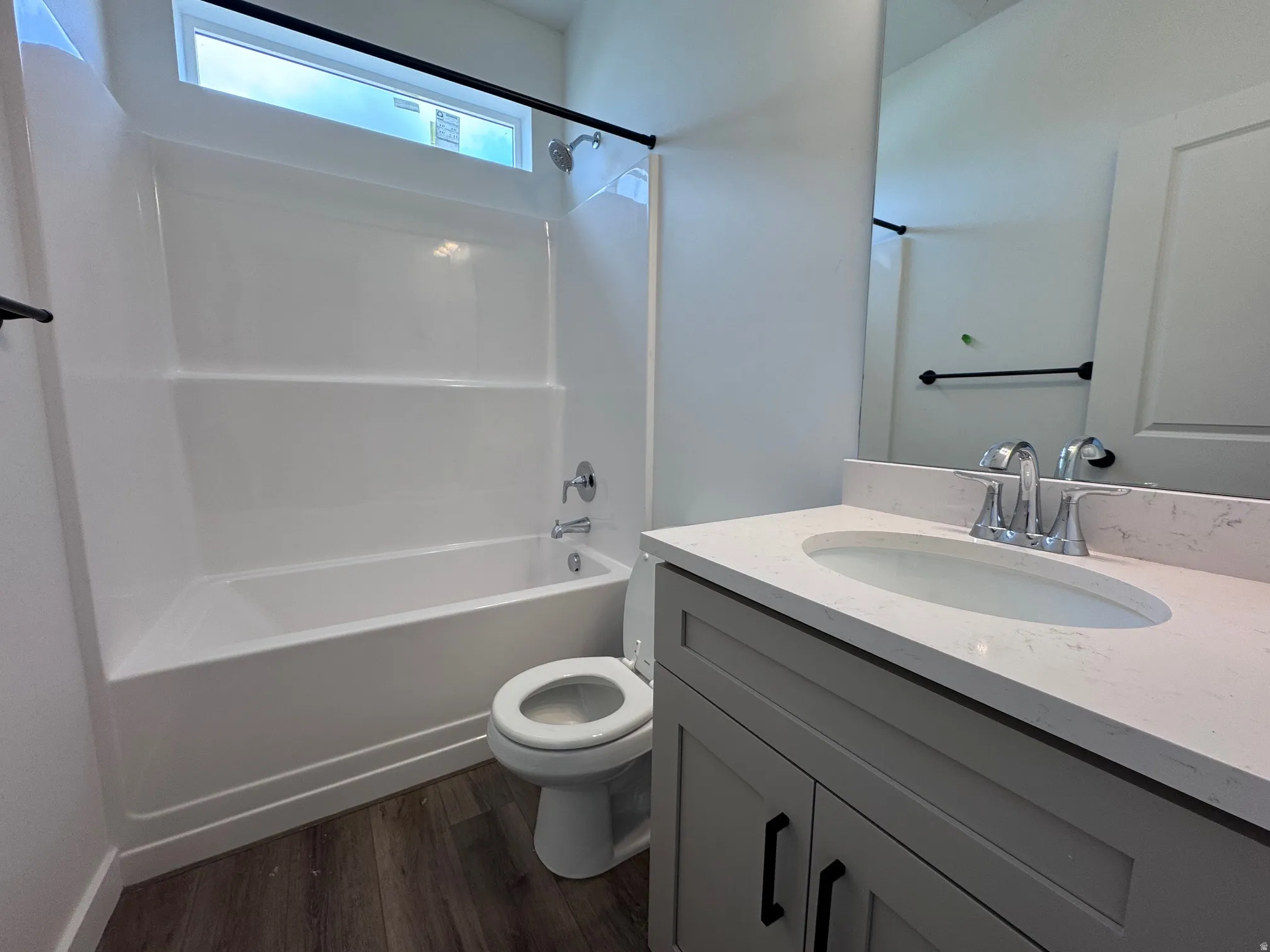 Full bathroom featuring a white tub with shower, a contemporary vanity with a light-toned countertop, and a large mirror