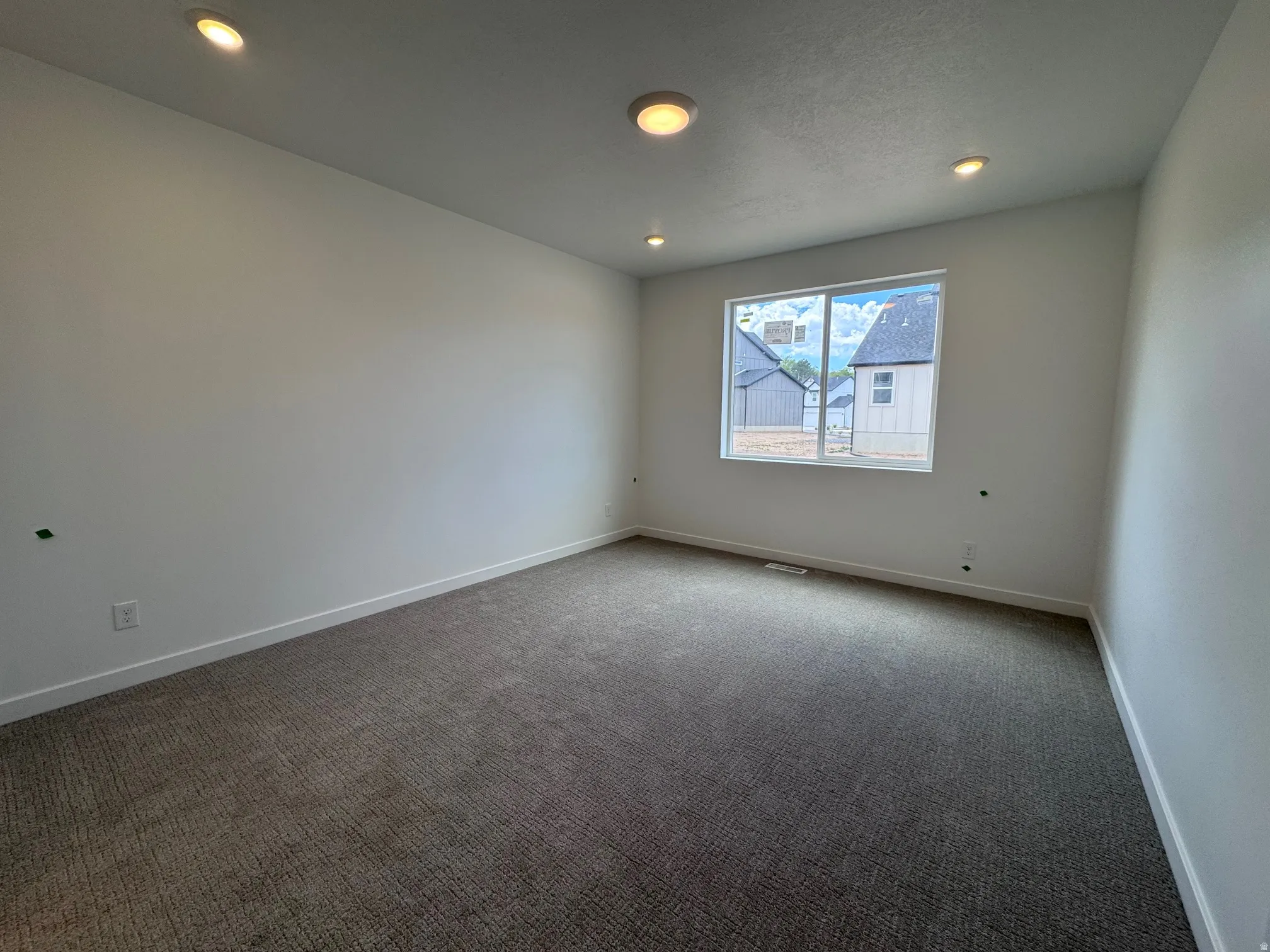 Spacious interior featuring a large window, recessed lighting, neutral carpeting, and crisp white walls