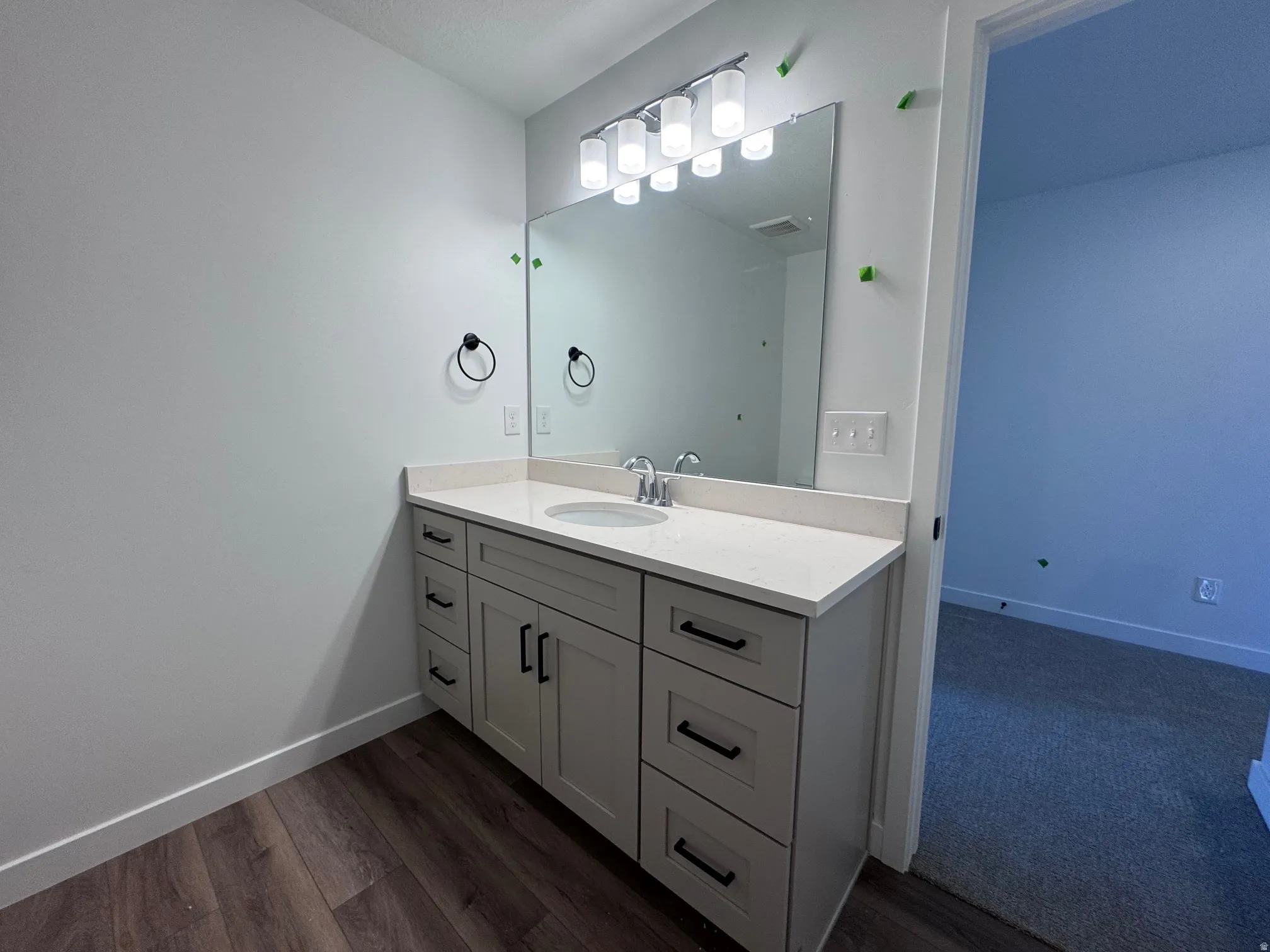 Bathroom featuring a single vanity with gray cabinetry, a light-toned countertop, and a rectangular undermount sink