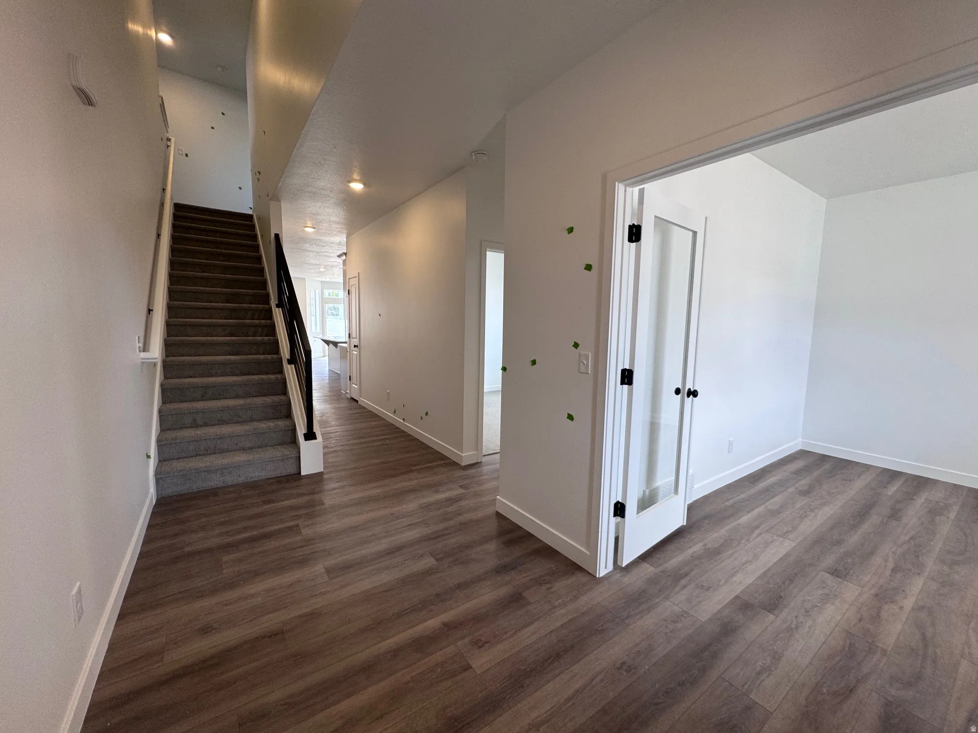 Entryway featuring wood-finish flooring and a carpeted staircase with a black metal handrail